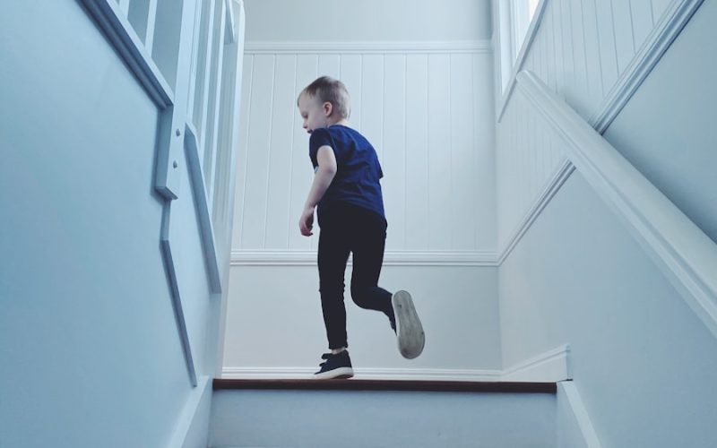 man in blue shirt and black pants sitting on white staircase