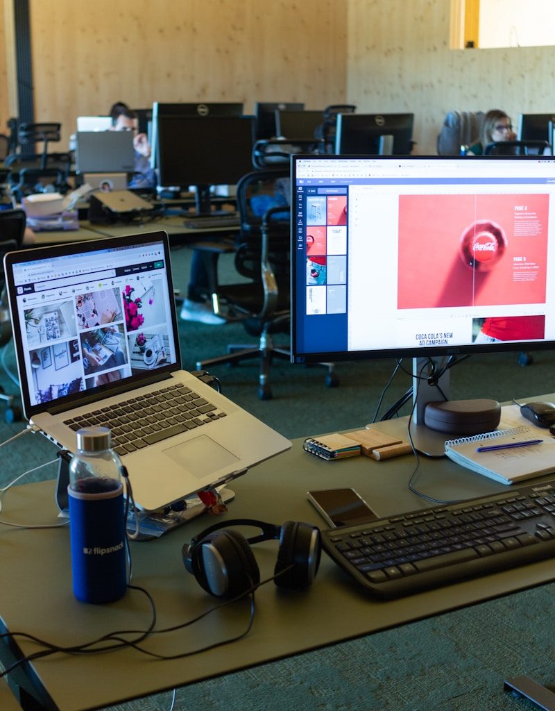 a desk with computers and a laptop