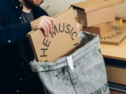 man in black jacket holding brown cardboard box