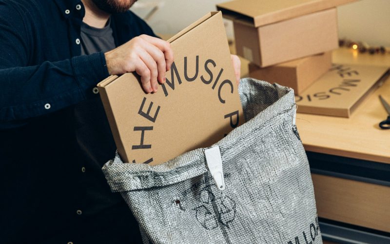 man in black jacket holding brown cardboard box