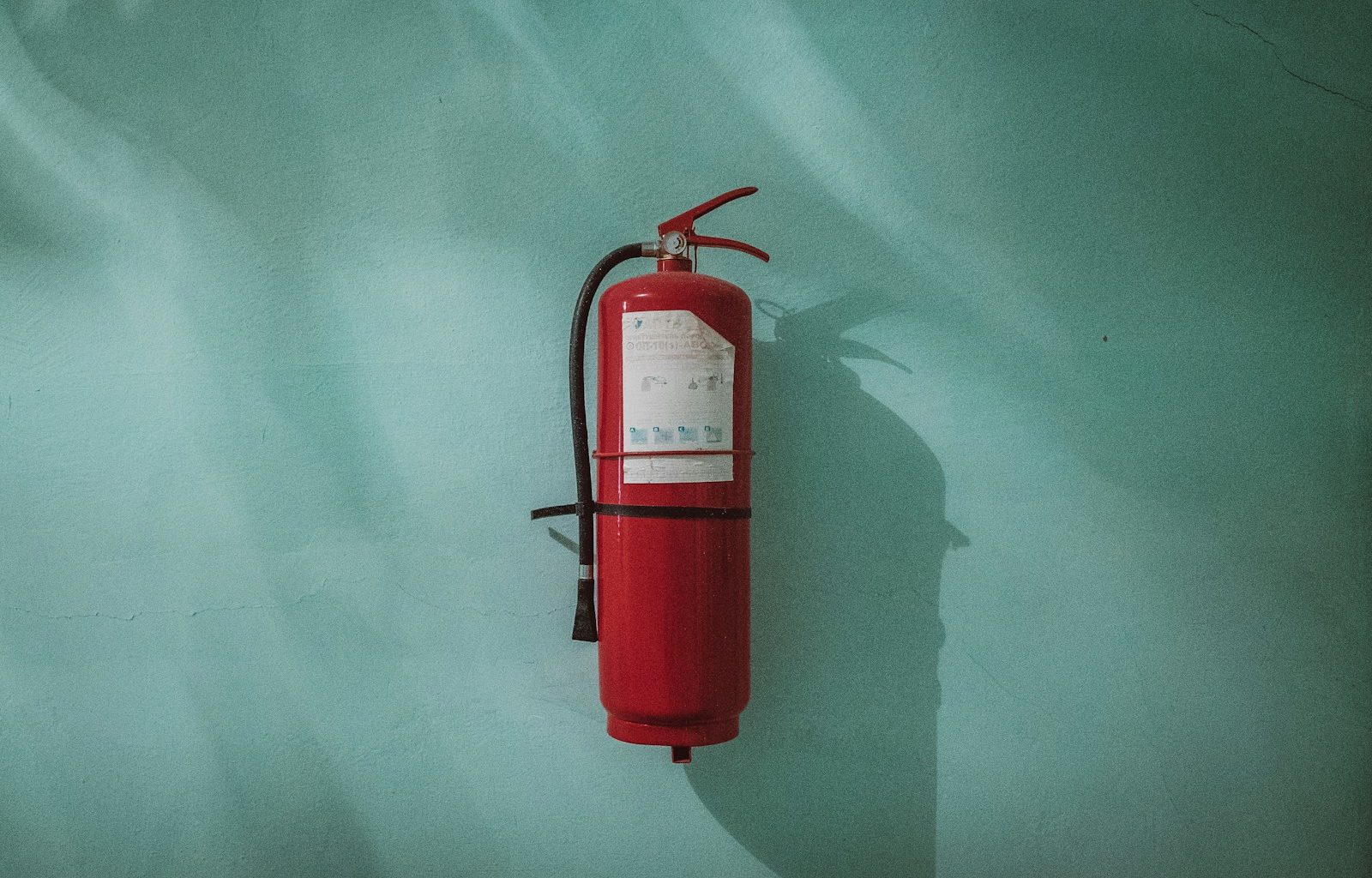 red fire extinguisher on green wall