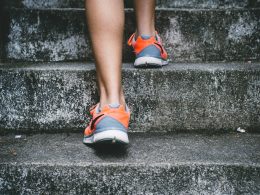 person wearing orange and gray Nike shoes walking on gray concrete stairs