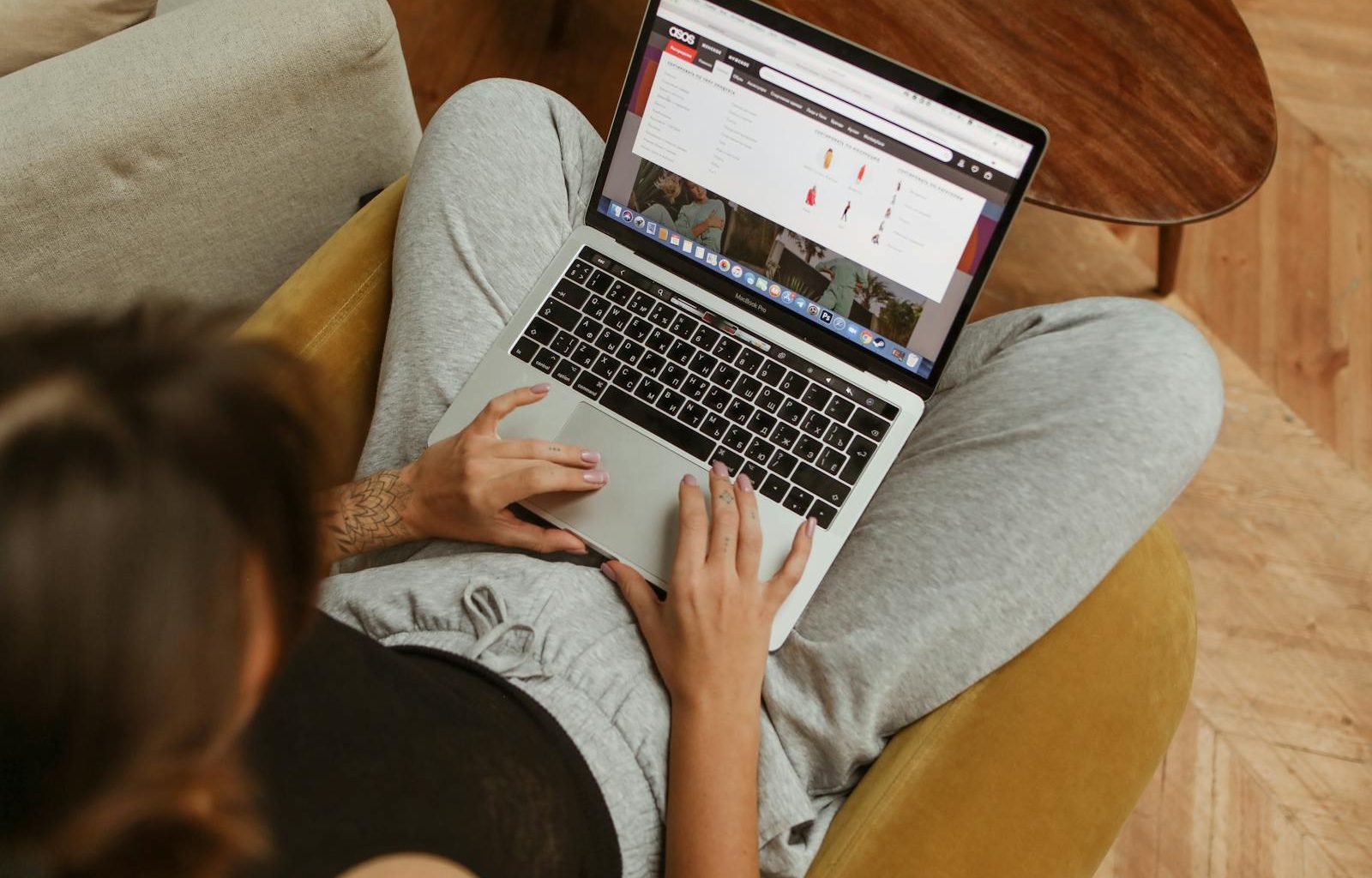 A person leisurely shopping online from home, using a laptop while sitting on a cozy chair.