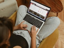 A person leisurely shopping online from home, using a laptop while sitting on a cozy chair.