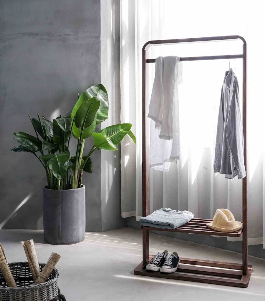 gray dress shirt hang on brown wooden rack in front of window with white curtain