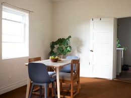 a room with a table, chairs and a potted plant