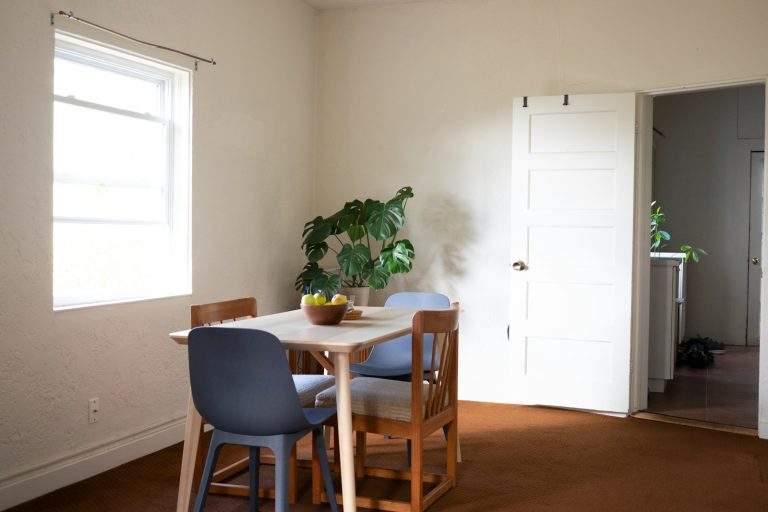 a room with a table, chairs and a potted plant