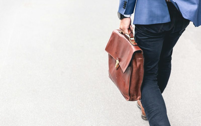 person walking holding brown leather bag